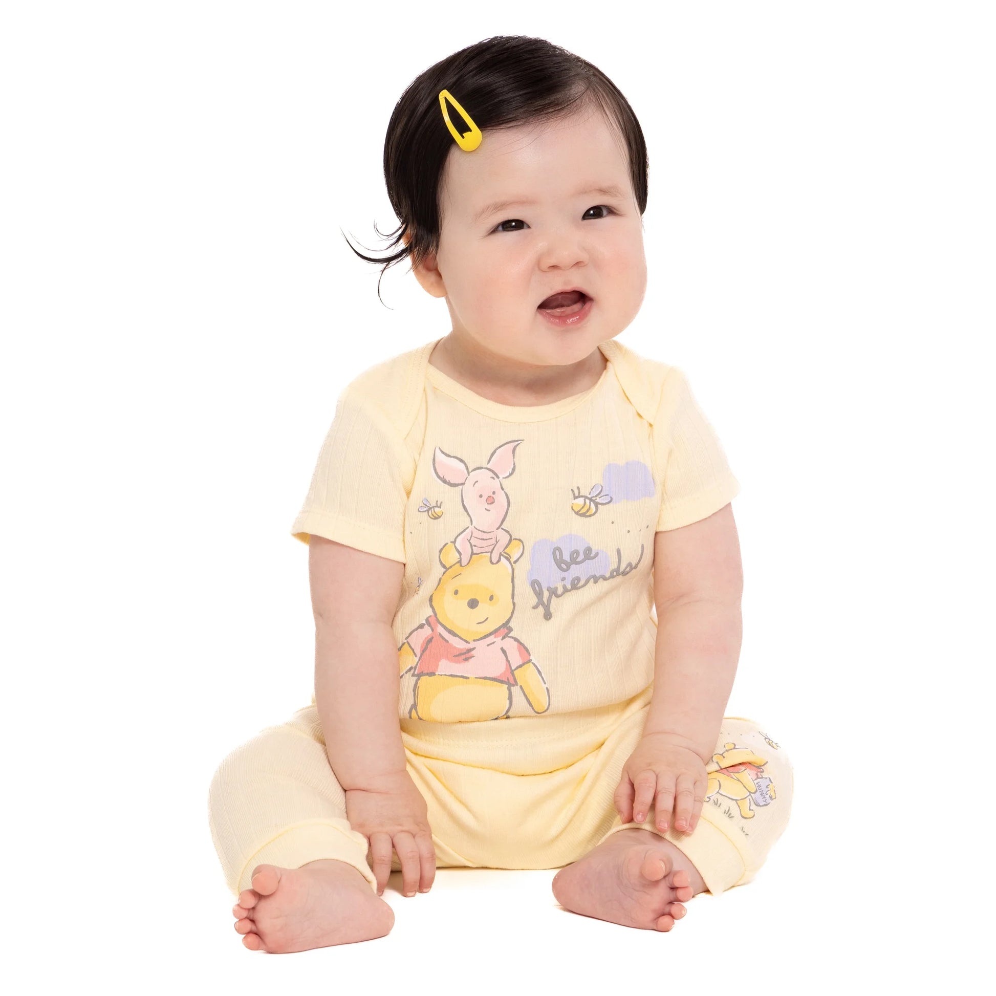 Baby wearing a yellow outfit with cartoon character on a white background