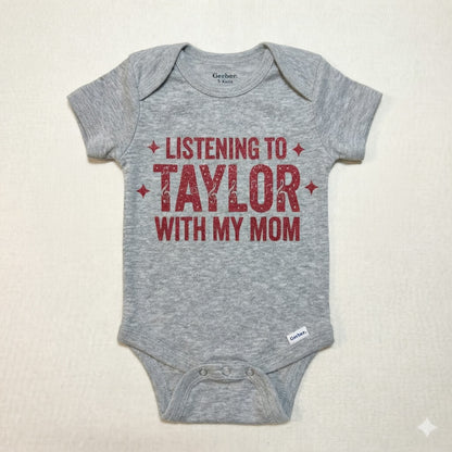 Gray baby onesie with red text 'Listening to Taylor with my mom' on a beige background