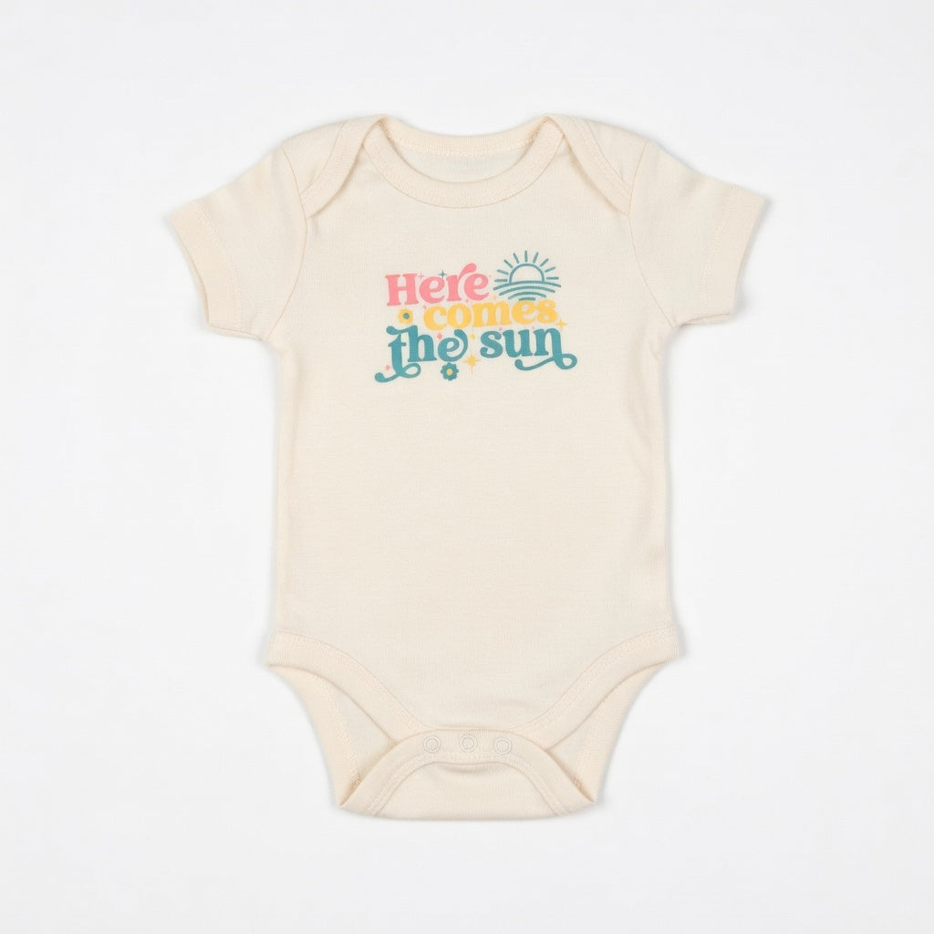 Beige baby onesie with 'Here comes the sun' text on a white background