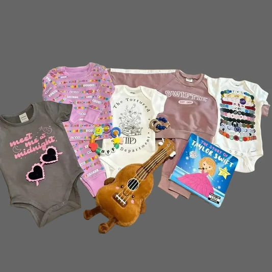 Flat lay of onesies with In My Baby Era newborn gift set with TTPD onesie.