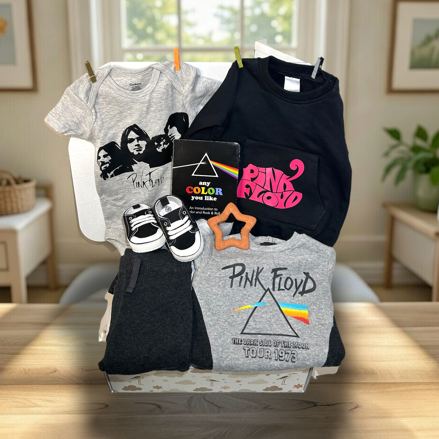 Collection of Pink Floyd-themed clothing and accessories on a table with a home interior background.