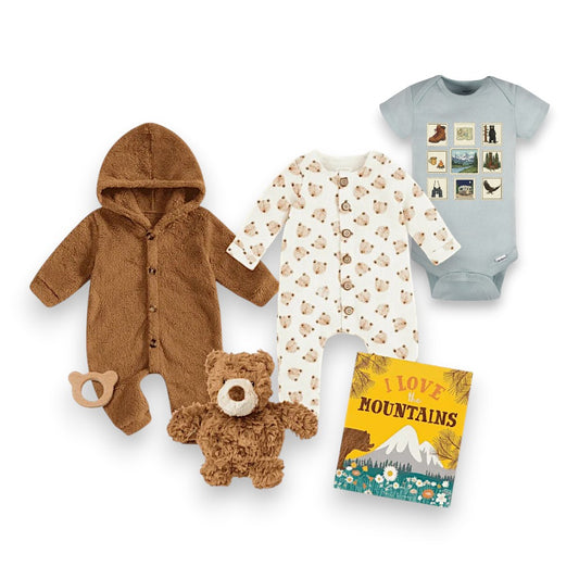 Baby clothing and toy set including a brown onesie, teddy bear, and 'I Love Mountains' book on a white background.