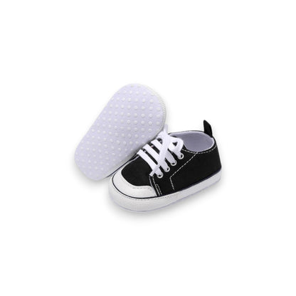 Black and white baby shoe with sole showing texture on a white background